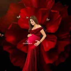 A bold and artistic statement. The mom-to-be stands like a queen before a giant red flower, creating a powerful and visually stunning portrait that is rich in color and symbolism.