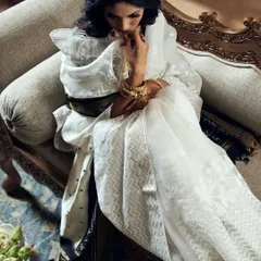 This shot captures a quiet, introspective moment. The soft lighting and elegant pose create a mood of sophisticated grace, highlighting both the texture of the white saree and the ornate gold jewelry.