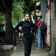A powerful, full-length portrait on a quiet lane. The all-black outfit creates a strong, confident silhouette.