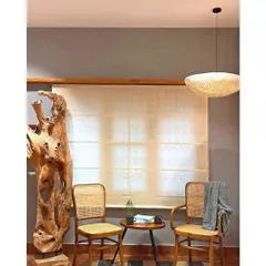 This cozy seating arrangement, featuring my teak and rattan chairs, is illuminated by a flattened globe pendant. The light fixture adds a layer of softness and texture to the clean lines of the room.