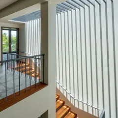 The play of light and shadow is a material we sculpt with. In our "The Mantle" project, these vertical fins cast dramatic, shifting patterns across the staircase, turning a simple transition space into a dynamic art installation.