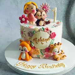 A woodland animal theme is perfect for a first birthday. This cake features cute, handmade fondant figures of a fox, deer, and squirrel among delicate flowers.