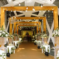 This warm and inviting entrance tunnel was created with rich yellow fabric and soft draping, illuminated by strings of Edison bulbs. The design offers a rustic yet elegant welcome, perfect for a grand wedding celebration at NESCO.
