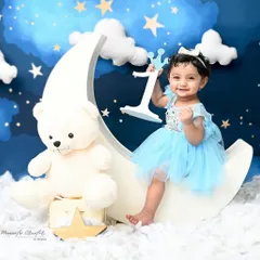 Over the moon for turning one! This little princess is celebrating her first birthday with a celestial-themed shoot, complete with a crescent moon, stars, and a fluffy teddy bear.
