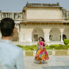 This over-the-shoulder shot creates a personal, story-driven perspective. It feels as if we are seeing the bride through her partner's eyes, running joyfully in the palace courtyard.