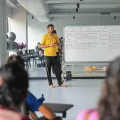 A trainer presents the key steps of CPR to an engaged audience of coaches and athletes, ensuring everyone understands the protocol.