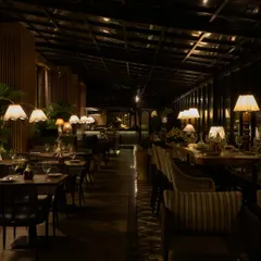 The evening ambiance at FIORI, where warm, low-level lighting from table lamps creates an intimate and cozy atmosphere. The design ensures that the space feels just as magical at night, with the glass structure reflecting the interior glow.