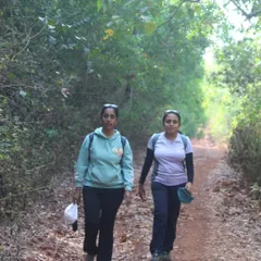 Two trekkers walking on a trail through the forest, part of the path connecting two beaches.
