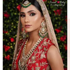 A portrait of bridal elegance. This bride wears a magnificent Kundan and pearl set with emerald drops, paired with a matching maang tikka and oversized statement earrings.