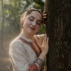 An intimate and serene portrait of the dancer. Leaning against a tree with her eyes closed, this shot captures a quiet moment of connection between the artist and nature.