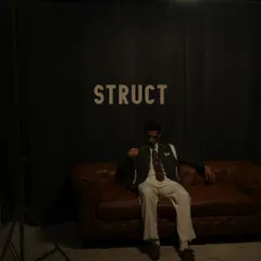 A moody behind the scenes shot from the Struct menswear campaign, showing the brand's logo on our wall and the model relaxing on our leather couch between takes.