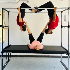 A creative and challenging three-person pose on the Cadillac. This kind of group work builds amazing strength, trust, and is a lot of fun.