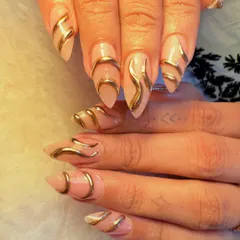 This design features bold, 3D gold chrome waves sculpted over a neutral, almond-shaped nail extension. The result is a futuristic, liquid-metal effect that is both edgy and incredibly glamorous.