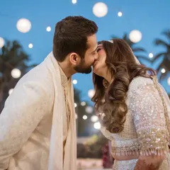 A perfect kiss against a backdrop of twinkling lights. We specialize in creating romantic couple portraits that feel both magical and authentic, like this beachside Nikaah moment.