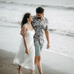 A candid shot of a couple walking along the shore. The natural light and the sea breeze create a beautiful, romantic atmosphere for pre-wedding photography.