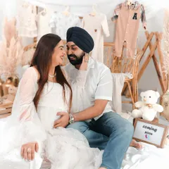 An intimate moment between an expecting couple, sharing a look of love and excitement. The soft lighting and dreamy setup highlight their connection.