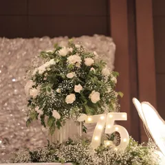 We incorporated illuminated marquee numbers into the floral decor to highlight the milestone. This glowing "75" nestled among white roses and baby's breath adds a touch of modern flair to the classic floral arrangement.