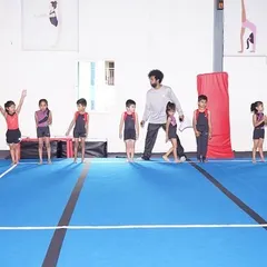 A coach leads a group of our youngest gymnasts, lining them up to practice their skills in a structured and encouraging environment.