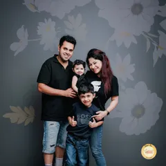 A classic family portrait against a floral grey backdrop. We focused on creating a comfortable pose that feels natural for the parents and their two young sons, all dressed in coordinated dark tops and denim.