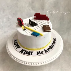 A cake for an architect, complete with edible blueprints, a measuring tape, and other tools of the trade. It's a simple yet thoughtful design that celebrates a person's profession.