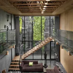 In this living space, a massive green wall serves as the backdrop, seen through a floor-to-ceiling glass facade. The design erases the barrier between the built and the natural, creating a tranquil oasis.