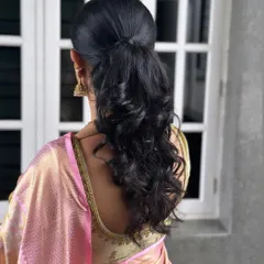 A modern half-up, half-down hairstyle with voluminous curls for Keerthi. This style is perfect for receptions and sangeets, offering a look that is both elegant and playful.