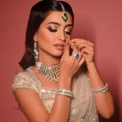 The final touches are just as important. Here, the bride adjusts her nose ring, showing a candid moment where the full artistry, from the glowing skin to the detailed jewellery, comes together.