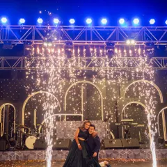 A moment of pure magic on stage. The couple is framed by glowing arches and a shower of cold pyrotechnics, creating an iconic, celebratory photograph. The design is all about creating these unforgettable moments.