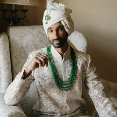 A regal portrait of the groom, his emerald necklace adding a touch of color to the classic ivory sherwani. I focus on capturing the quiet confidence and poise of the groom on his wedding day.