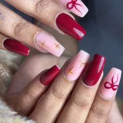 A cute and bold design featuring cherry red nails paired with a soft pink base. The accent nails are adorned with hand-painted red bows and tiny gold stars, creating a look that's playful, chic, and anything but basic.