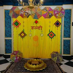 A traditional Haldi backdrop with bright yellow drapes, Rajasthani umbrellas, and colorful hangings, perfect for a classic and festive celebration.