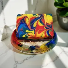A vibrant, multi-colored swirled soap bar resting in a matching custom soap dish. I love seeing my creations in their final home, adding a pop of color to the bathroom.