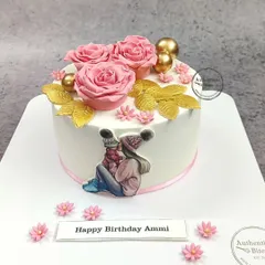A sweet "Supermom" cake featuring a touching illustration of a mother and child. The cake is adorned with pink roses and golden leaves, making it a perfect birthday gift for Ammi.