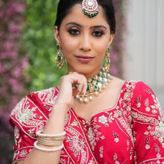 A close-up of a bride wearing a Kundan and emerald choker. This look is perfect for coordinating with green accents in a bridal lehenga.
