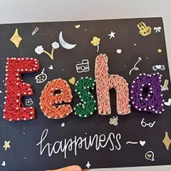 A close-up of a beautifully finished string art name board for "Eesha". The colorful letters and hand-drawn doodles make it a truly personal piece of decor.