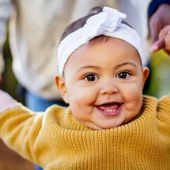 That big, gummy smile is just the best. This close-up captures the pure happiness of a baby who is learning to stand with a little help.