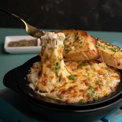 The strongest pull of all. A fork pulling up a cheesy bite of baked mac and cheese, showcasing the creamy, gooey texture of the dish.