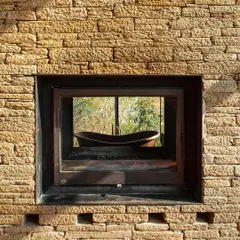 A window at the Himalayan home frames a view of an outdoor bathtub, blending the intimate act of bathing with a direct connection to the rugged, natural setting.