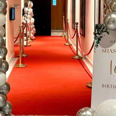 A red carpet entrance for a glamorous 18th birthday party. Silver and white balloon pillars and a welcome sign complete the VIP experience.