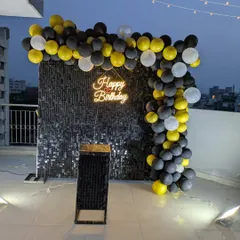 This wide shot shows how the sequin wall and balloon arch create a defined party corner on an open rooftop.