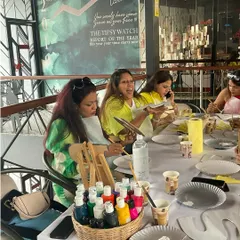 The table is set for a fun kitty party. With a basket of colorful paints and drinks on hand, these ladies are ready to unleash their creativity.