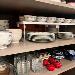 Using an adjustable shelf riser, I've doubled the storage space in this cabinet. The dinner plates are stacked below, while the matching bowls are organized on top, making the entire set easy for staff to access.
