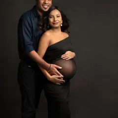 A timeless and classic portrait. Both partners looking at the camera, sharing this moment with the world, their hands together on the bump.