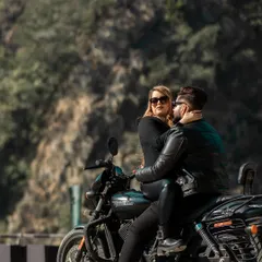 An intimate and edgy shot of the couple on a Harley Davidson, set against the rugged mountain terrain. This kind of adventure pre-wedding photography is perfect for couples who share a love for the open road.