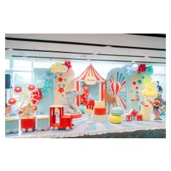 A grand circus stage setup, complete with a red-and-white striped big top, a Ferris wheel, a circus train, and life-sized elephant and giraffe props.