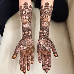 A very dense and detailed design covering the hands and arms, featuring elephants, peacocks, and lotus flowers. This is for the bride who wants a truly traditional and full look.