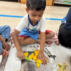 Practical life skills are at the core of my program. Here, a young child practices concentration and fine motor control by carefully cutting a mango, learning independence and contributing to a real-life task.