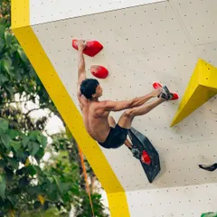 This dynamic move, known as a 'dyno', shows the athleticism required in psicobloc climbing. The climber is airborne, reaching for the next hold.