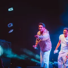 Capturing candid interactions is key to concert photography. Here, the artist shares a lighthearted moment with the audience and his bandmate.