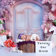 Another pose from the floral gate session, with a lightbox marking the baby's one-month milestone. The abundance of pink and purple flowers creates a lush, dreamy atmosphere.